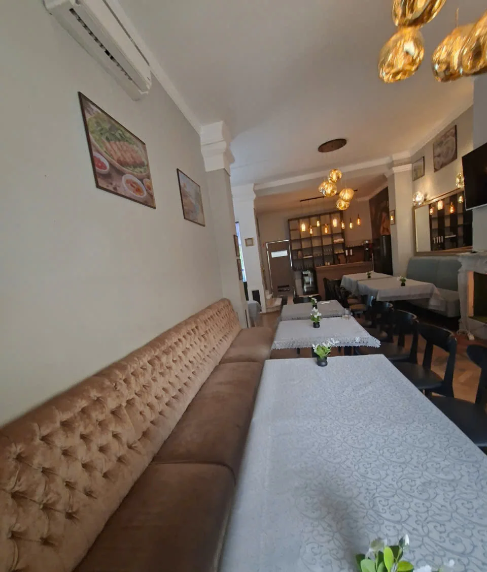 Sala lungă cu banchetă, mese și corpuri de iluminat aurii
