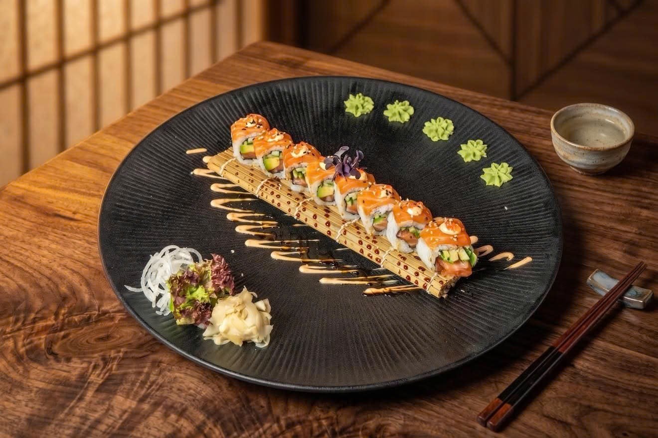 Sushi-Rolle mit Lachs auf einem schwarzen Teller